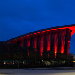 Proue dans la végétation, le palais des sports éclairé en rouge ardent. ©Raphaël Charuel